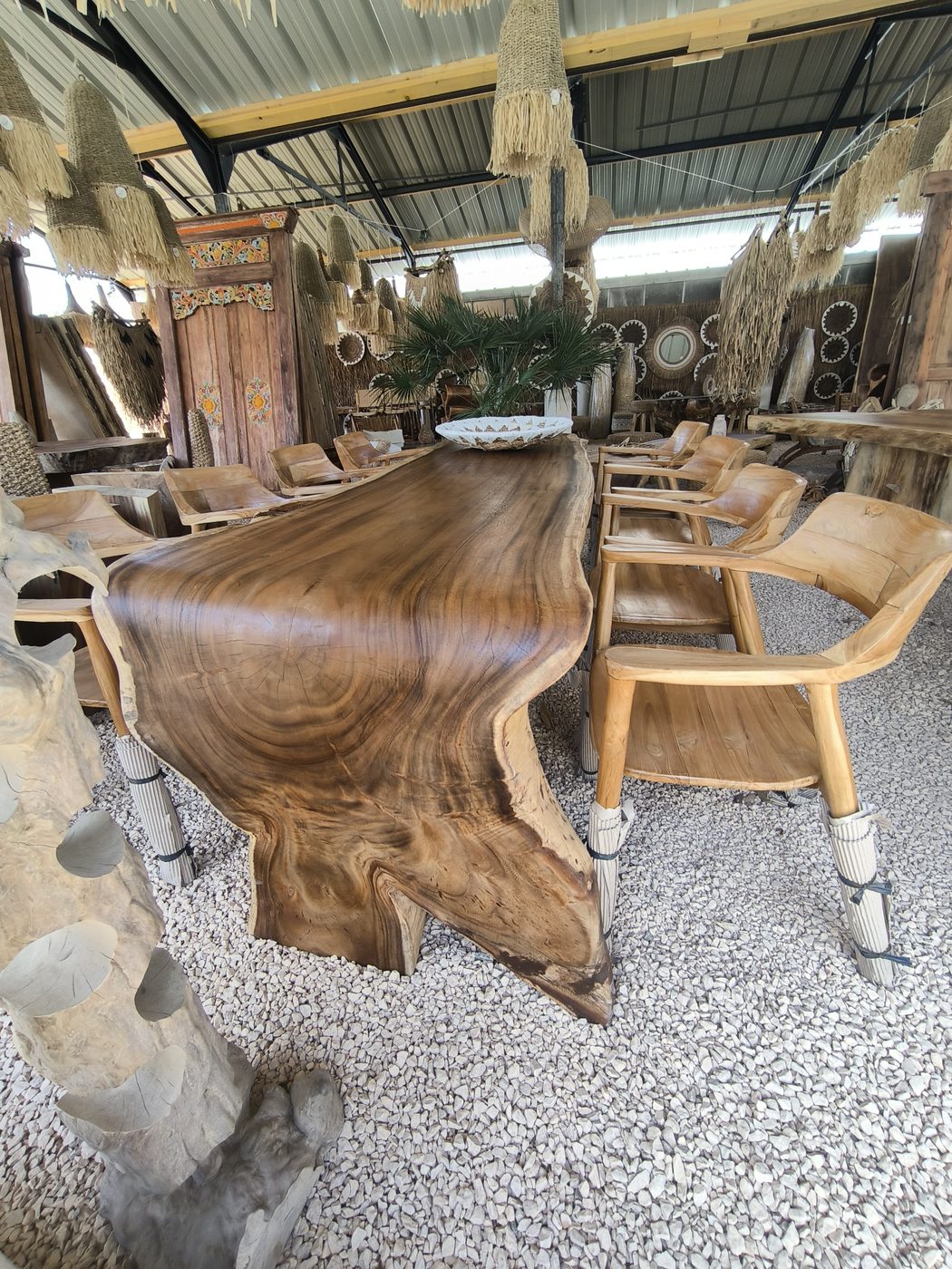 Grande table en suar massif entourée de chaises en teck, sous la serre de la pépinière